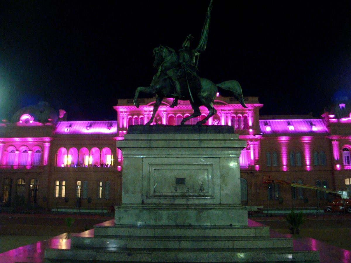 La Casa Rosada iluminada de rosa por la noche detrás del monumento a Belgrano